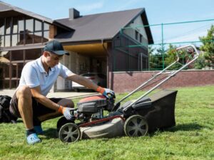 Man adjusts lawnmower as he does fall lawn care to prepare his lawn for winter